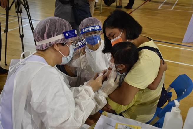 家长紧抱孩子安抚，鼓励孩子们勇敢面对打疫苗。（谢明俊摄）