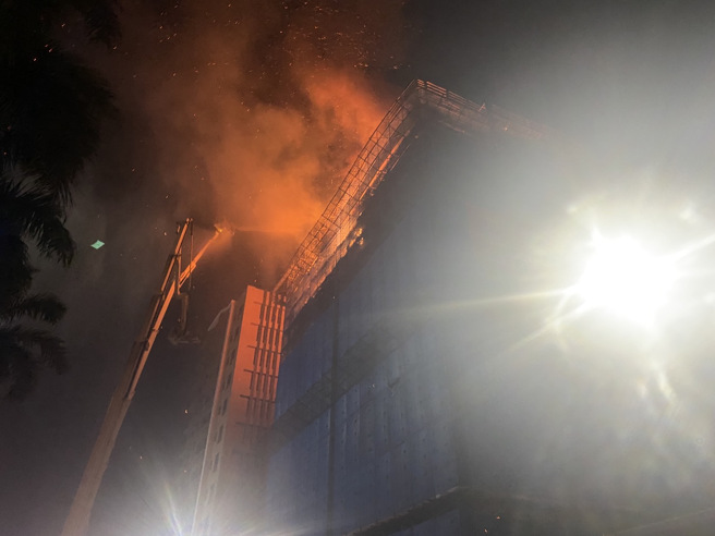 新北市三重1处工地大楼，「9至10楼全面燃烧」消防人员登云梯车灌救。（新北消防局提供）