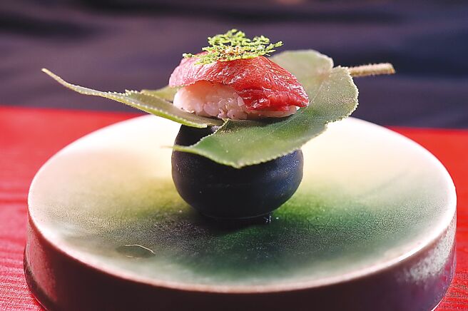 〈黑鲔鱼大腹握寿司〉上层有自制〈昆布仙贝〉与金箔搭配，醋饭内拌着蟹肉，并用「乌贼盐辛」与现磨山葵提味。图／姚舜