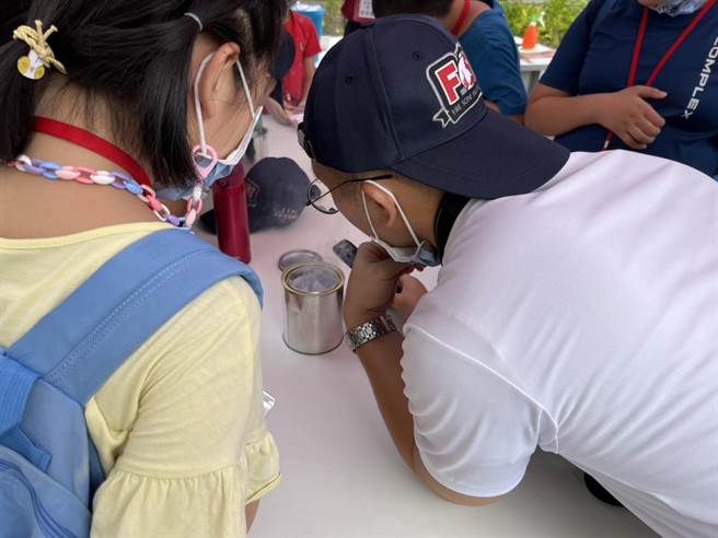 学童们想尽办法煽风、吹气，以帮助火苗燃烧。（陈梦茹摄）