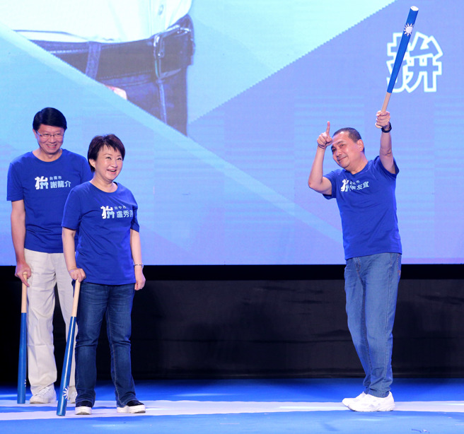 国民党第21届第2次全国代表大会28日在国立体育大学综合体育馆举行，寻求连任的新北市长侯友宜（右）上台挥棒造势，用手比了中外野方向，象徵全垒打宣言，台中市长卢秀燕（中）在一旁笑开怀。左为台南市长参选人谢龙介。（黄世麒摄）