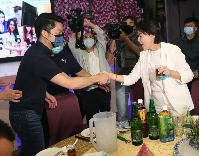  国民党台北市长参选人蒋万安（左）与台北市长参选人黄珊珊（右）28日同时出席滨江市场福德宫「福德正神圣诞千秋」平安餐会，两人在贵宾席上相会，互相握手致意。（郑任南摄）