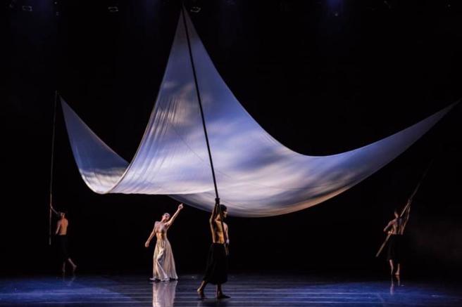 实景歌舞剧「潮海渡」以当代手法重新诠释传统养殖文化，竹篙与硕大三角巾延展，表达过去在港湾中阡陌的插枝养殖地景，而舞者身影作为先民在大鹏湾沿海生活的村妇与渔夫，透过舞蹈与光影布幔的交织呈现往昔沿岸聚落的常民美学。（图/ 中央社）