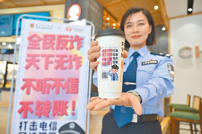 为扫荡电信网路诈骗，大陆公安部组织指挥江苏、浙江、安徽3省15市公安机关，展开夏季治安打击整治「百日行动」于近日收网，抓获各类涉诈违法犯罪嫌疑人1.3万名。图为一名南寧市女警展示印有反诈骗标语的手摇饮。（中新社）