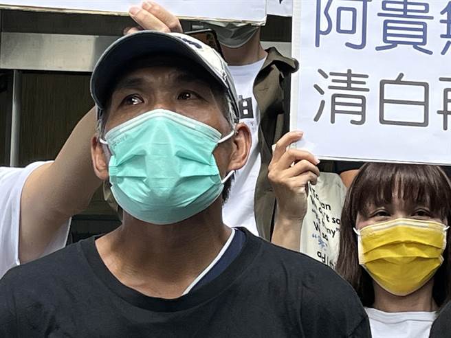 林案宣判結束，林男在冤獄平反協會工作人員陪伴下走出高雄高分院，面對穿越烏雲灑落的陽光，多次望向天空，眼淚止不住。（袁庭堯攝）