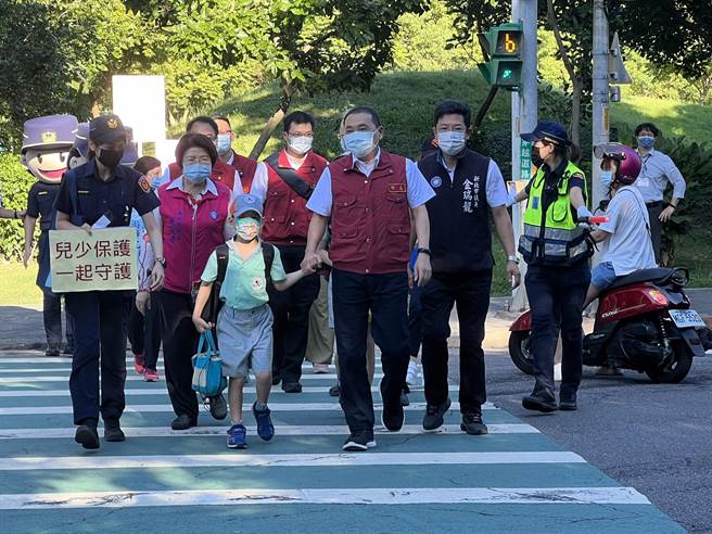 侯友宜牽著小朋友的手過馬路到學校。（王揚傑攝）