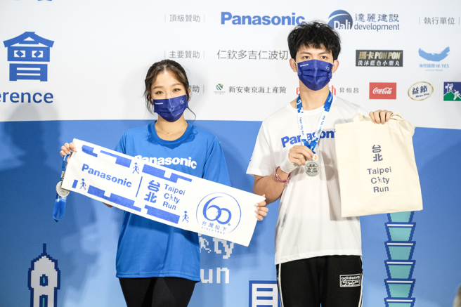 明日之星冠军歌手赖慧如（左）、郭忠佑（右）展示2022 Panasonic台北城市路跑赛完赛毛巾和提袋。（大会提供）