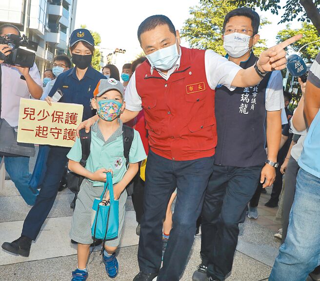 新北市長侯友宜（中）30日前往光復國小關心開學防疫落實情形，並護送小學生過馬路進校門。（劉宗龍攝）