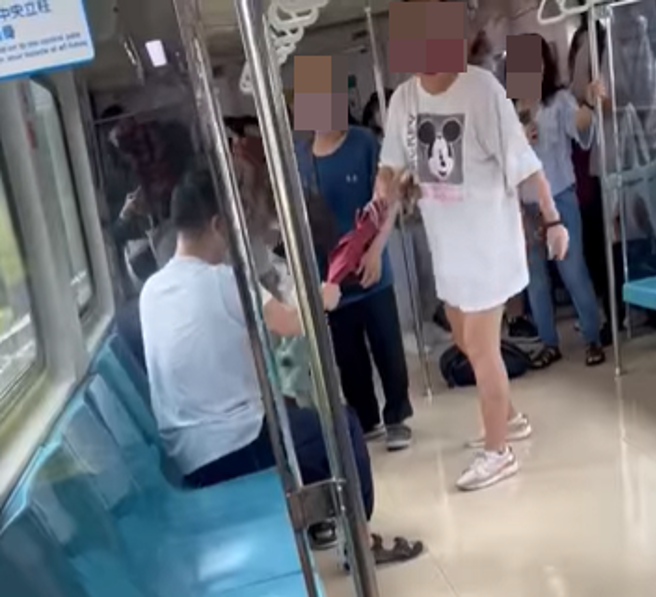 白色女子拿着红色长雨伞制止座位上男子往前攻击。(翻摄脸书爆料公社)