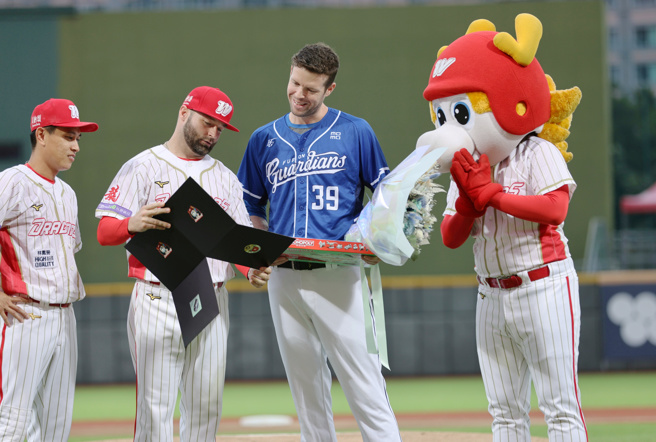 富邦悍将洋投罗力（右二）在2日迎来生涯最终战，1日赛前味全龙由队长吴东融献上花束、好友伍铎则送上特制桌游。（味全龙提供）