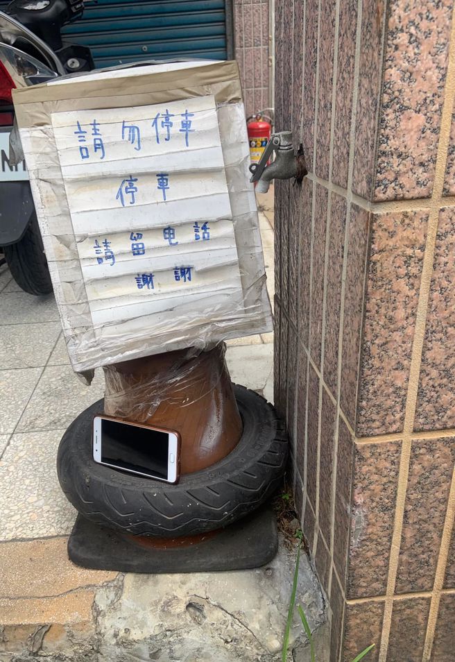 1名屋主製作告示板告知自家門口不能停車，若真的停了需「留下電話」，沒想到後來該告示板下方竟真的出現1支「真的電話」。（翻攝自臉書「路上觀察學院」）