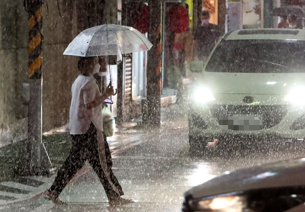 軒嵐諾颱風逼近台灣，帶來了間歇性的風雨，民眾撐傘穿越馬路。（鄭任南攝）