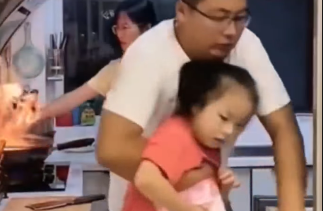 夫妻在廚房煮飯，妻子的炒菜鍋突冒出火焰，丈夫一看嚇壞，順手將一旁的女兒抱起衝出廚房並關門，留下妻子在裏頭，妻子最後面露凶光準備打人。（翻攝自臉書「爆廢公社公開版」）