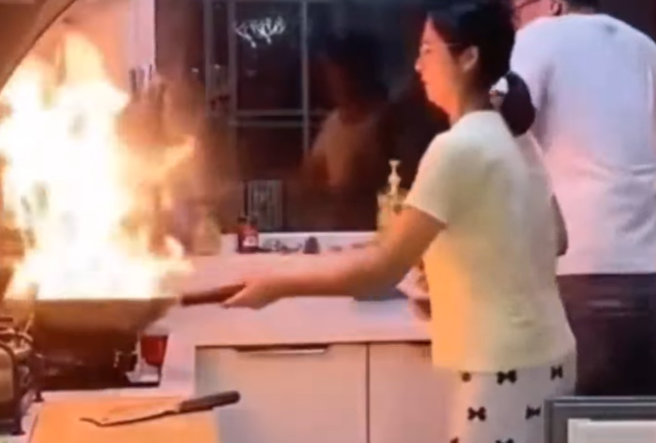夫妻在廚房煮飯，妻子的炒菜鍋突冒出火焰，丈夫一看嚇壞，順手將一旁的女兒抱起衝出廚房並關門，留下妻子在裏頭，妻子最後面露凶光準備打人。（翻攝自臉書「爆廢公社公開版」）