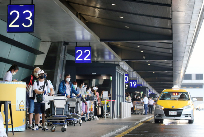 本土新冠肺炎持續升溫。圖為在桃機第一航廈外，剛入境的旅客排隊搭乘防疫計程車。（范揚光攝）