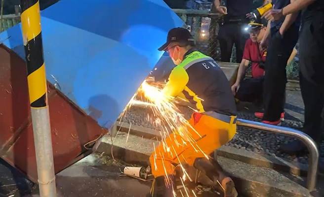 基隆市消防员持切割器切开回收箱锁头，将妇人救出。（读者提供／陈彩玲基隆传真）