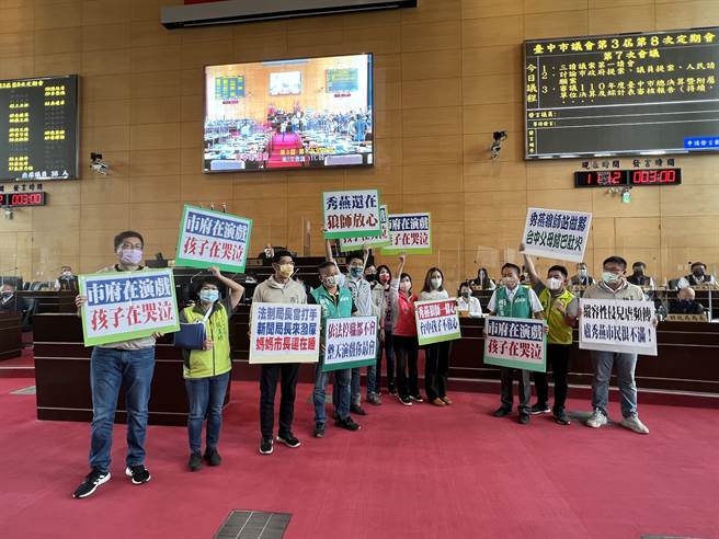 民進黨台中市議員一字排開，高舉寫有「依法停職都不會，整天演戲你最會」手板，要求市長說明狼師處理方式。(林欣儀攝)