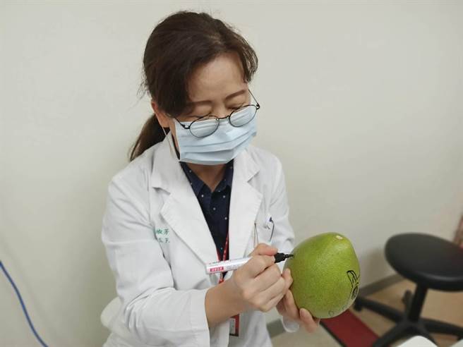 林淑芳巧手在柚子上彩绘。（为恭医院提供／李京升苗栗传真）