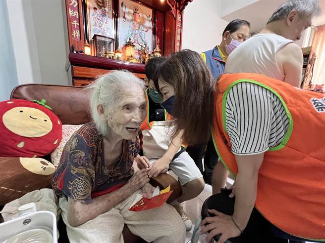 蔡衍明爱心基金会课长江曼华紧握陈妇双手，陪其聊天。（李奇叡摄）