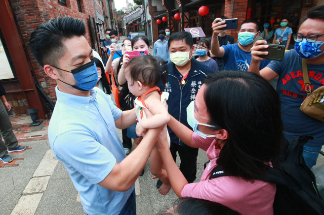 有民眾要求合影，国民党台北市长参选人蒋万安还亲切地抱起孩子，展现父爱的一面。（陈信翰摄）