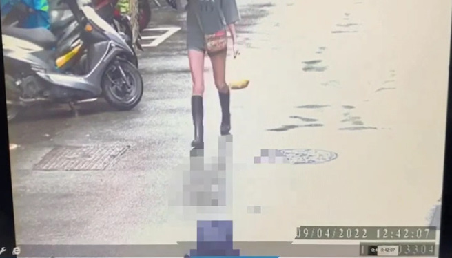 死者大哥梁嫌下雨天抱著2袋屍塊淋雨走在街道上，其背後有位長腿妹卻不知冷血分屍兇嫌走在前面。（翻攝畫面）