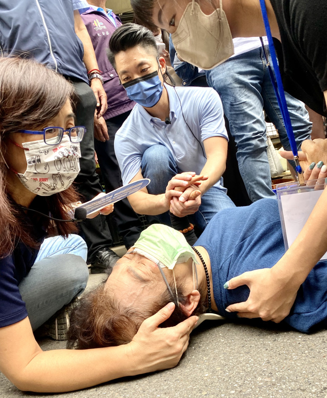 國民黨台北市長參選人蔣萬安（中後）7日前往白蘭市場掃街拜票，因市場擁擠，一名婦人摔倒在地，蔣握住婦人手關心慰問，等待救護車。（郭吉銓攝）