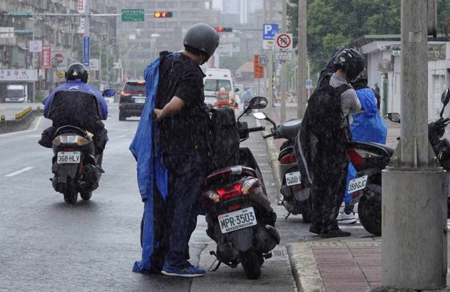 机车骑士面对突降雨势，赶紧停车穿雨衣。（黄子明摄）