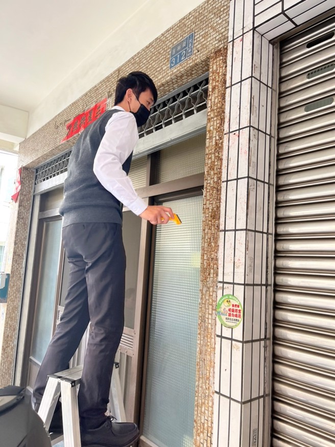 后驿商圈内多中古透天，屋主年龄也多偏高，信义房屋后驿店同仁过年之前，会主动协助张贴春联，替社区增添年味。图为段展綦进行社区服务、帮长辈贴春联。（图/信义房屋提供）