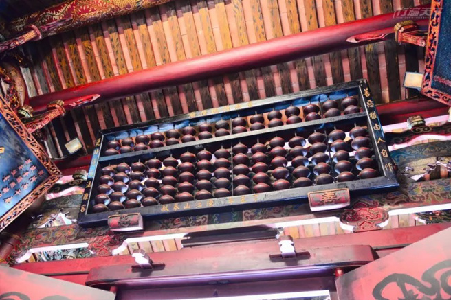 城隍廟裡懸掛的大算盤，象徵城隍爺依據往生者生前善惡功過進行審判。（圖/ 行遍天下）