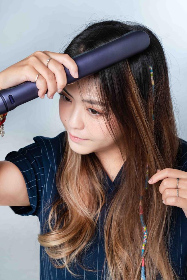 使用飞利浦温控护色水润直卷两用负离子美髮造型器时，可在做上层头髮造型时，以造型器夹住头顶根部的头髮开始推高，制造蓬松度。（石智中摄）