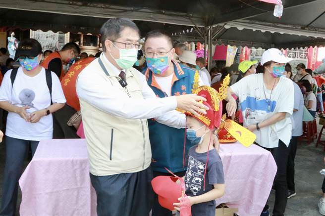 市长黄伟哲随后也前往济安宫与民同乐，当场玩起射箭游戏及套圈圈活动，并帮得奖的小朋友戴上状元帽。（台南市府提供／李俊淇台南传真）