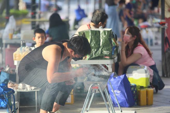 天母幫2022年百人大會烤10日晚間在大葉高島屋百貨前廣場舉行，圖為一位民眾努力生火。（張鎧乙攝）