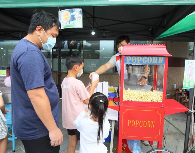 天母幫2022年百人大會烤10日晚間在大葉高島屋百貨前廣場舉行，圖為工作人員分送剛做好的爆米花。（張鎧乙攝）