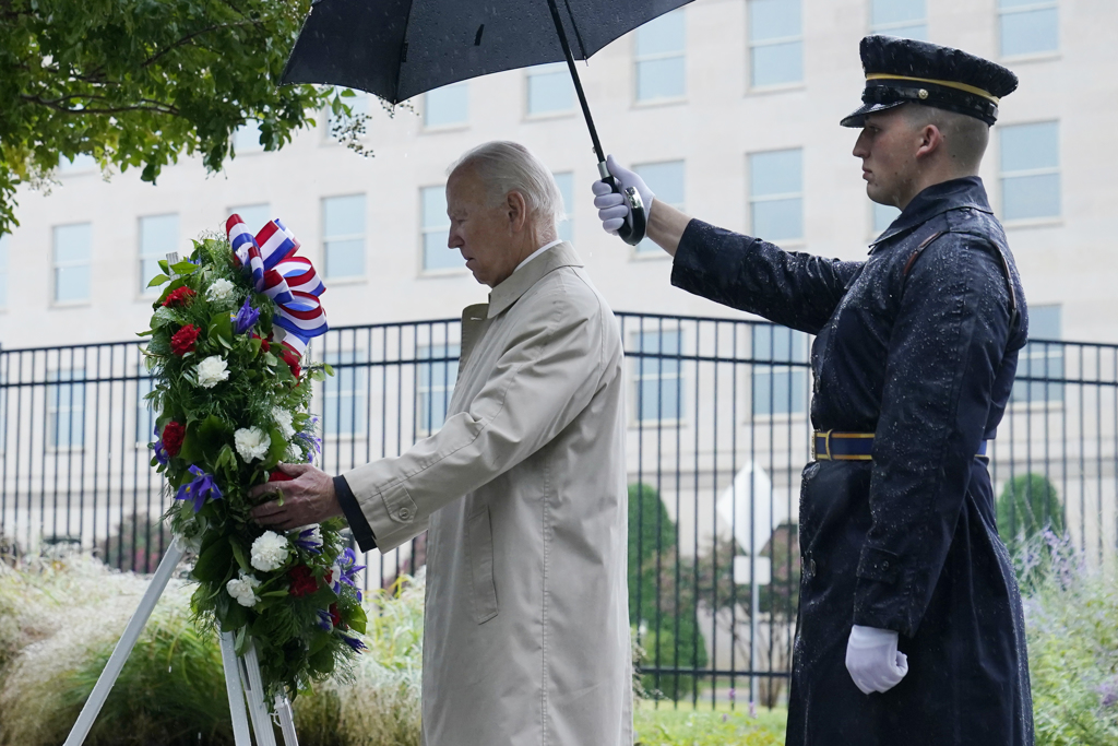 美国总统拜登前往当年遭遇攻击的地点，在连绵不断的雨势中献上花圈后，将右手放在左胸的心脏位置。图/美联社(photo:ChinaTimes)