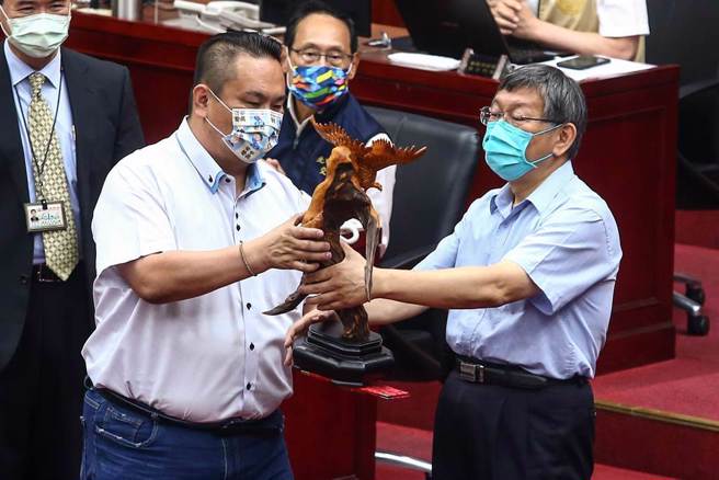 台北市长柯文哲（右）12日赴议会备询，这也是市长柯文哲任内最后一次总质询，市议员陈重文（左）特别送上一尊展翅高飞的老鹰木雕，祝福柯文哲卸任后「鹏程万里」，柯市长也欣然接受亲手接下这祝福。（邓博仁摄）
