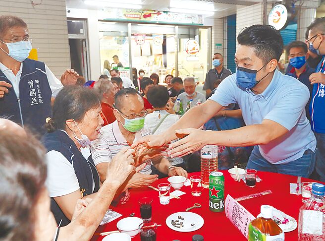 国民党台北市长参选人蒋万安痛批，政府百般阻挠疫苗採购，转而当起高端推销员，民间买到疫苗后，陈时中又来揽功抢着去机场接机、接疫苗，让民眾看了非常反感。图为蒋万安（右）11日出席台北市中庄仔福德宫圣诞平安宴，逐桌向参加活动的民眾拜票，寻求支持。（刘宗龙摄）