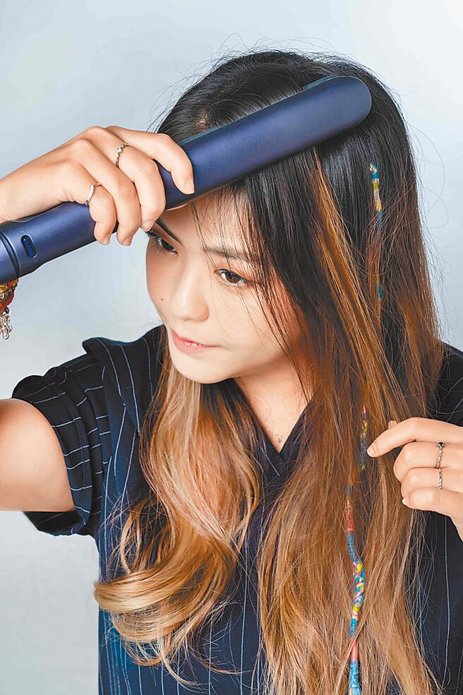 使用飞利浦温控护色水润直卷两用负离子美髮造型器打造人鱼卷造型时，可用一边前后翻转造型器、一边往下移的手法。（石智中摄）