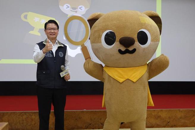 法务部调查局长王俊力（左）14日出席国安动画发布记者会，介绍由调查局吉祥物黄喉貂「查查」（右）担纲演出的国安动画。（图/ 中央社）