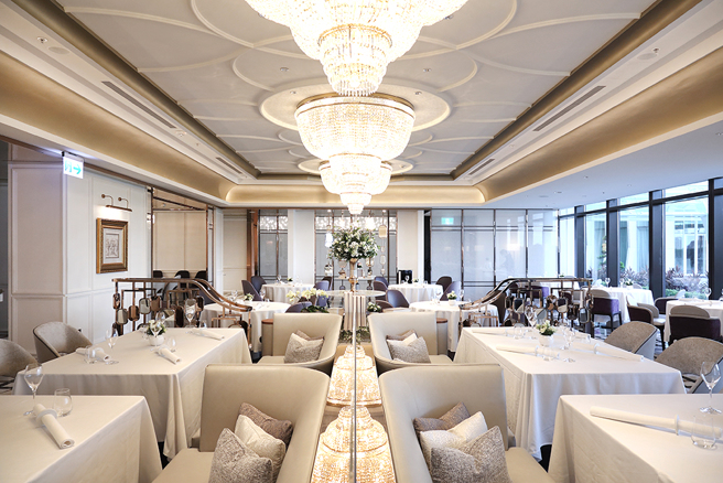 白与金构成明亮高雅的空间主调，垂吊的水晶吊灯下装饰绽放的鲜花，「美享地餐厅」展现法式沙龙的优雅。(摄影/Carter)