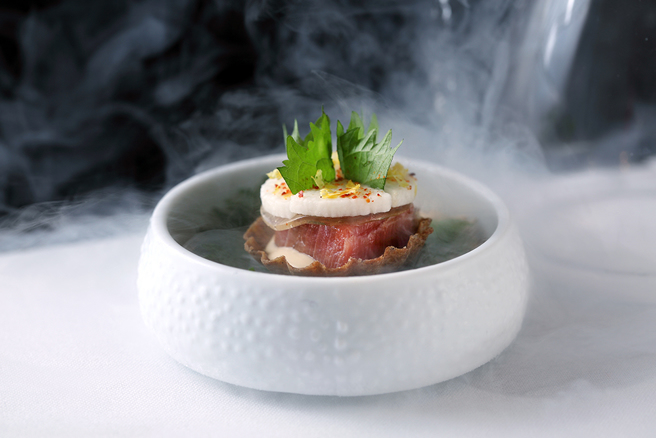 透明蛋形容器掀开的瞬间，液态氮烟雾缓缓溢散，盘中小塔如云上仙岛，令人惊喜的饮食体验从视觉展开。小塔底层是牛肝箘和昆布制作的薄脆塔壳，主角为经数日熟成后浅渍酱油的日本鸟取县黑鲔鱼赤身，紫苏分别以新鲜草叶和佐酱的方式上下包夹，味道平衡爽口不张扬。(摄影/Carter)
