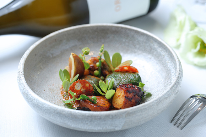 臺湾章鱼水煮后炭烤，口感弹牙，颇有野性气息。酱汁从韩式泡菜发想，加入西谷米、虾夷葱及发酵后的大根制作，菠菜叶包覆微辣的西班牙腊肠、无花果和发酵大根，点缀马齿苋菜、菁芳草和落葵花，有如精心设计的餐盘花园，味道则充满西班牙Tapas风情。(摄影/Carter)
