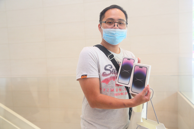 蘋果直營店16日開賣iPhone 14，排在首位的30歲沈姓男子（如圖）開心領取預訂的兩支iPhone 14 Pro Max 128GB深紫色機型。（張鎧乙攝）
