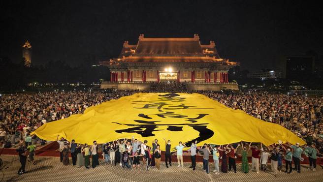  挥别三年来疫情的限缩，云门舞集总算又重返国家两厅院户外广场公演，2万名观眾携家带眷在秋月下看舞，演出结束出现大惊喜，广场上展开长44公尺、宽22公尺的巨幅布条，上面写着「勇敢向前」。（云门舞集提供）