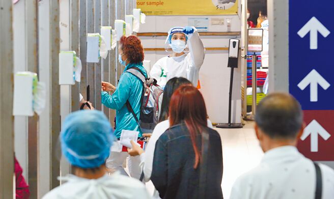 新冠肺炎本土疫情连4日破4万例，昨日共新增4万1430例本土、240例境外移入。图为桃园机场採检站，检疫人员引导旅客排队採检。（范扬光摄）