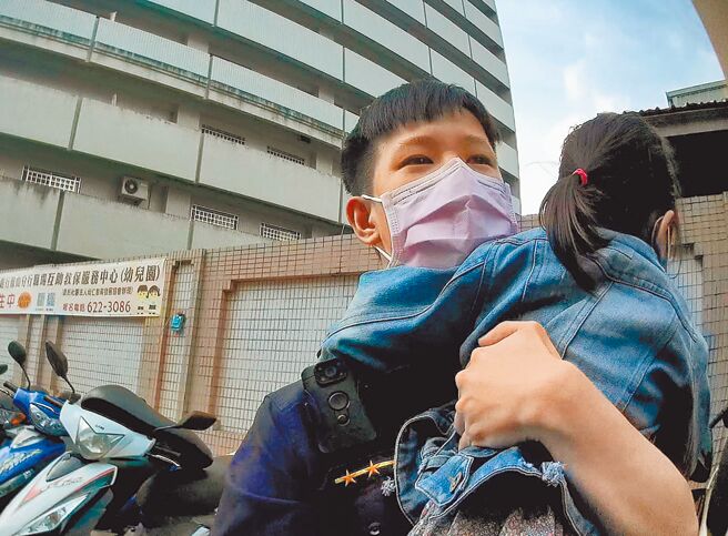 女童与阿嬷走散后蹲在路旁嚎啕大哭，员警上前询问后，一把将女童抱起，前往附近寻找阿嬷身影。（高市凤山分局提供／杨舒婷高雄传真）