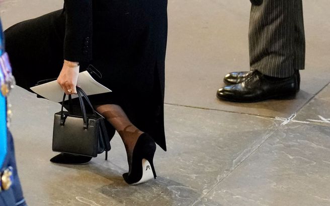 梅根一双名为「加油」(Pump It Up)的无带高跟鞋意外引起话题，鞋后藏着英文字母P和A合成的符号。 (图/路透社) 