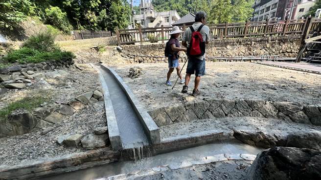 宝泉桥温泉露头冒出一堆黑油，引来游客围观。（张毓翎摄）