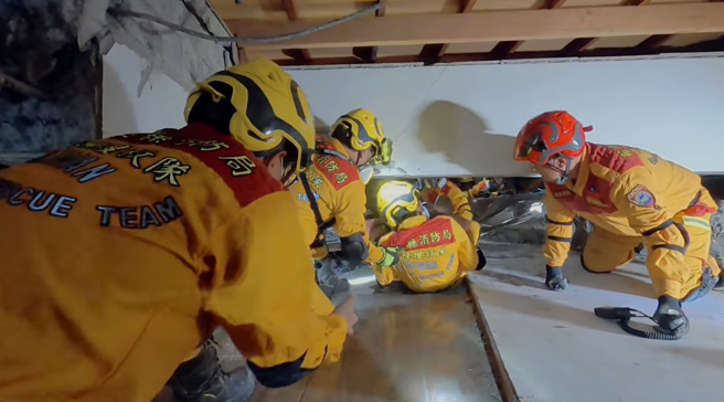 救難人員冒著餘震不斷的危險，進入倒塌的樓層，將受困的婦人墊在救難人員身體上，慢慢的拖出救援成功。（消防攝手 蔡哲文授權提供）