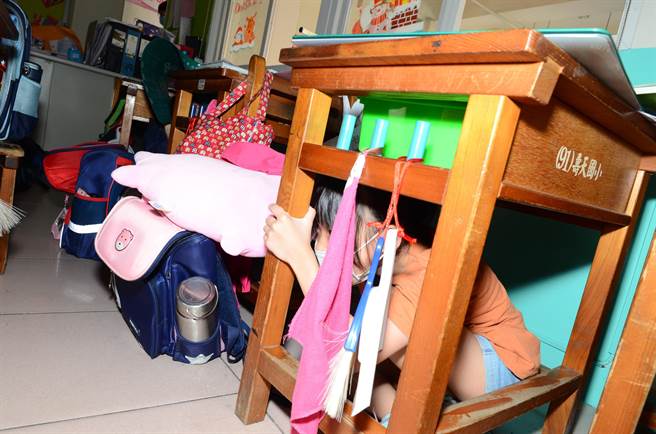 模拟芮氏规模4地震，高雄市冈山区寿天国小学生躲到桌下避难。（林瑞益摄）