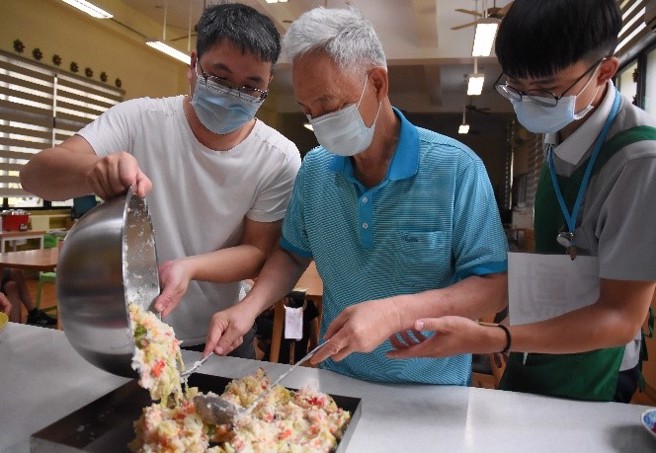 职能治疗师王玠钧协助阿公完成马铃薯沙拉。(照片/慈济科技大学提供)